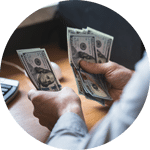 A small circular image of a man sorting dollar bills.