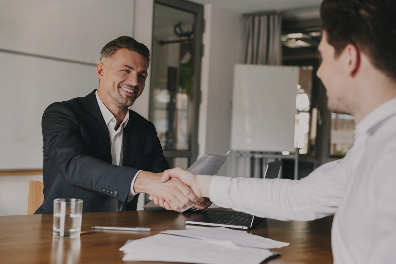 An male interviewer shakes the hand of an interviewee