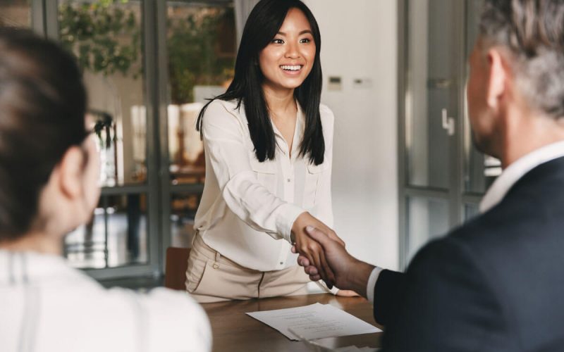 A woman smiles and shakes the hand of a man at the start of an interview.